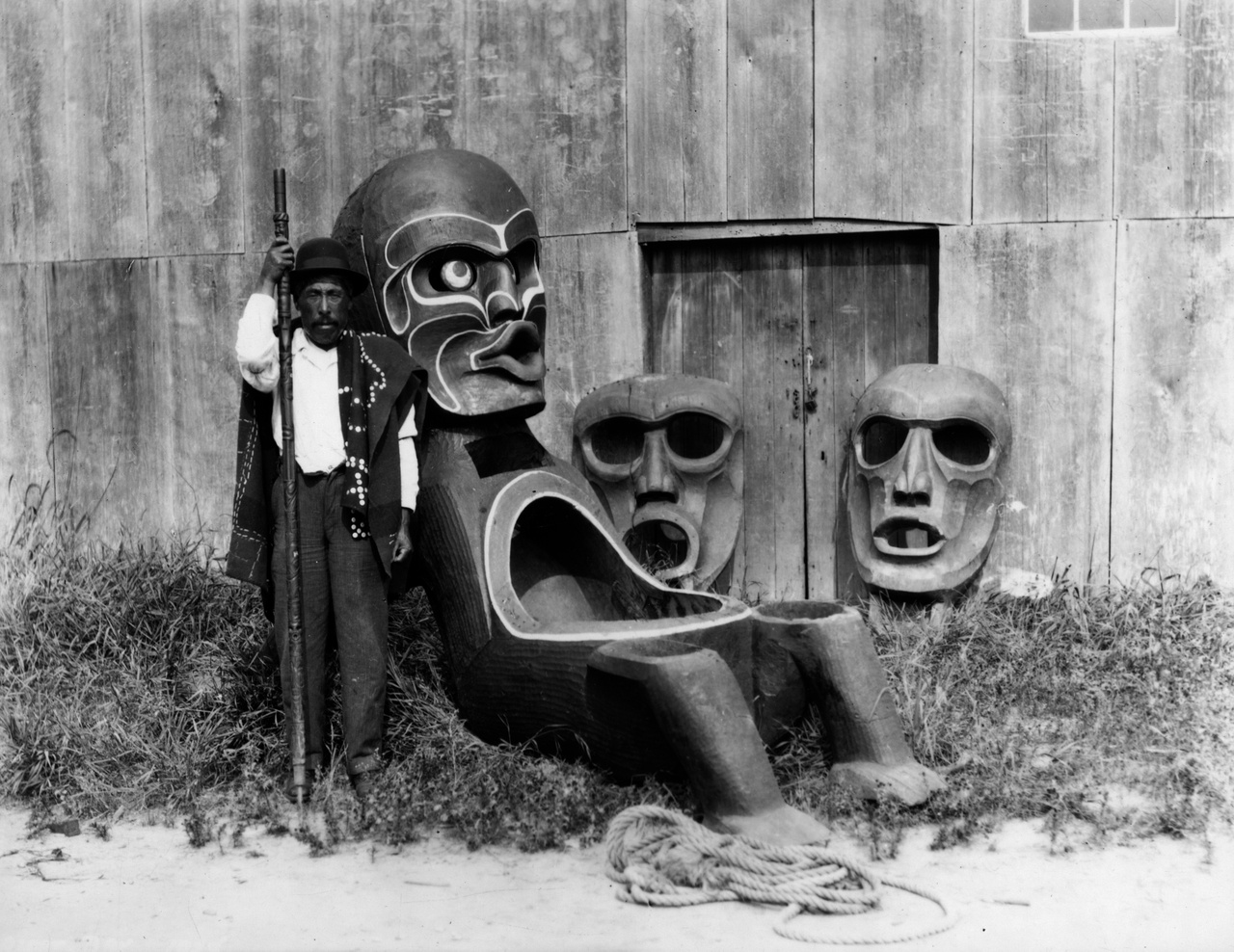 Chief Jim Humchitt (Kodi from Dzawad’enuxw) with potlatch bowl, masks, talking stick, and button blanket / mit Potlatch-Schale, Masken, Redestab und Knopf-Decke, Kingcome Inlet, 1926