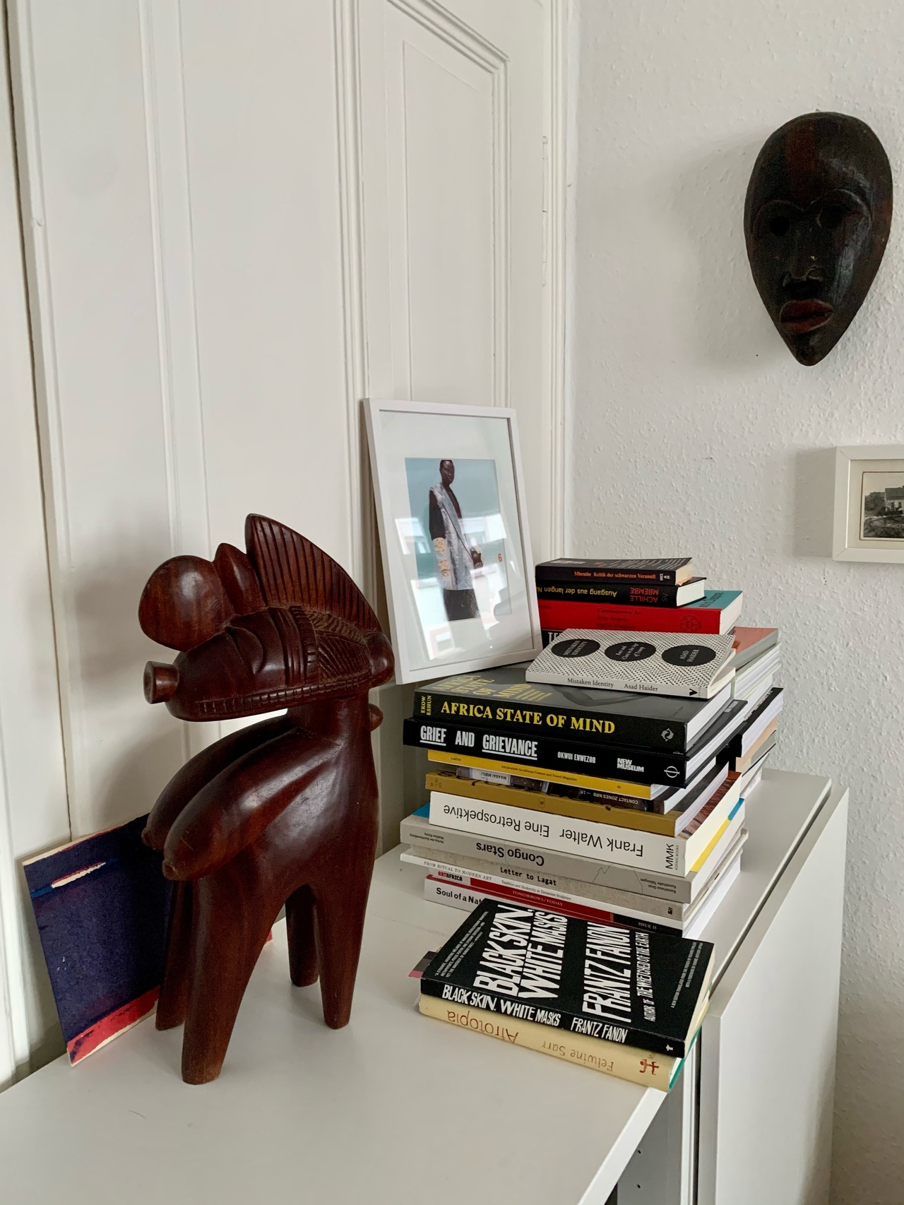 Nimba-Fruchtbarkeitsgöttin, vermutlich aus dem heutigen Guinea, und Feuerläufer-Maske aus Mali mit zufälliger Auswahl an Büchern der Autorin in ihrer Frankfurter Wohnung.